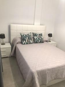 ein Schlafzimmer mit einem weißen Bett und zwei Nachttischen in der Unterkunft La Gaviota in Arrecife