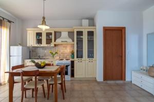 a kitchen with white cabinets and a table and chairs at Villaki in Maroulás