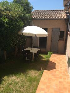uma mesa de piquenique com um guarda-chuva no quintal em Un petit coin sympa em Draguignan