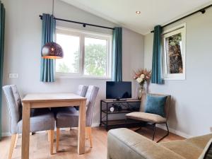 a living room with a table and chairs and a tv at Nieuw! OK40 Landelijk gelegen Chalet in Oostkapelle