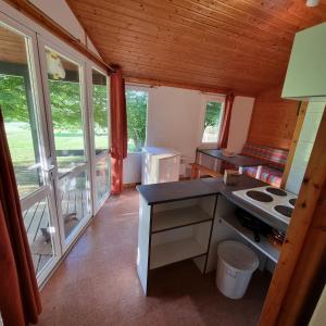 een keuken met een fornuis en ramen in een huisje bij La Forêt Enchantée in Cornille