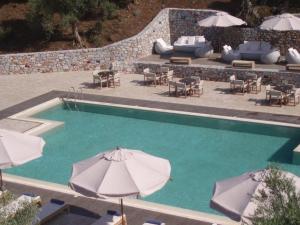 a swimming pool with umbrellas and tables and chairs at Belle Helene Hotel by GHH in Vathi