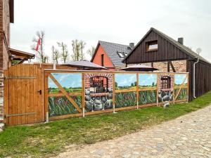 Ein Zaun mit einem Wandbild einer Farm drauf. in der Unterkunft Ferienwohnung Oberuckersee OT Melzow UCK 1152 in Melzow