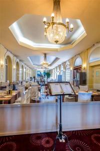 a restaurant with a bar and a chandelier at Hôtel Le Royal Promenade des Anglais in Nice