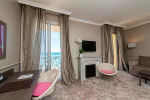 a living room with a table and chairs and a fireplace at Hôtel Le Royal Promenade des Anglais in Nice