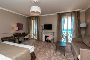 a hotel room with a bed and a couch at Hôtel Le Royal Promenade des Anglais in Nice
