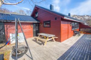 uma cabina vermelha com uma mesa de piquenique num deque em Fidjeland Holiday Home em Sinnes