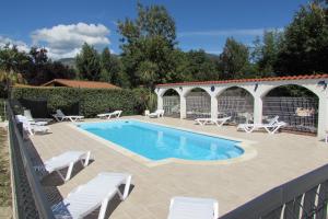 a swimming pool with white chairs and a patio at Les chalets du Verger des Ascarines in Corneilla-de-Conflent