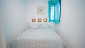 biała sypialnia z łóżkiem z niebieskimi akcentami w obiekcie Apartamento Los Patos Beach w mieście Benalmádena +37 zdjęć
