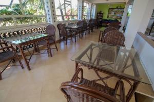 uma sala de jantar com mesas, cadeiras e janelas em Resort Coqueiral em Candolim