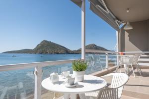 a white table and chairs on a balcony overlooking the ocean at Nelly's Apartments in Tolo