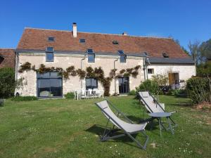 une maison avec deux chaises de jardin devant elle dans l'établissement La Grange, à Savonnières