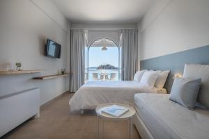 una camera d'albergo con due letti e una finestra di Nelly's Apartments a Tolo