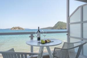 a table with a glass of wine and two chairs at Nelly's Apartments in Tolo
