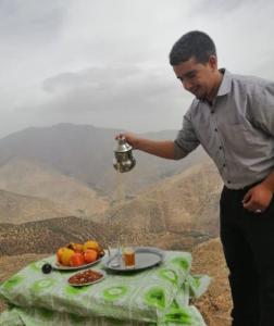 a man is standing next to a table with food at Hotel la belle vue 2100m in Taroudant