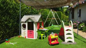 a garden with a pretend play house and a swing at Le Cottage de Maé in Seigy