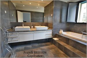 een badkamer met 2 wastafels, een bad en een spiegel bij Le Patio Centre ville PEZENAS in Pézenas