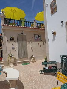 eine Terrasse mit gelben Sonnenschirmen an der Seite eines Gebäudes in der Unterkunft Moradia Meca - Casas para Férias in Nazaré