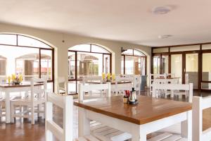 a restaurant with white tables and chairs and windows at Lapeng hotel, conference and wedding venue in Eikenhof