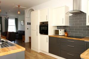 a kitchen with white cabinets and a microwave at 2 Yr Hen Fanc in Aberaeron
