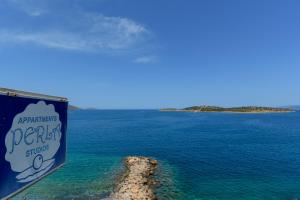 a sign for a bar on the ocean with a rock in the water at Perla Apartments in Agios Nikolaos