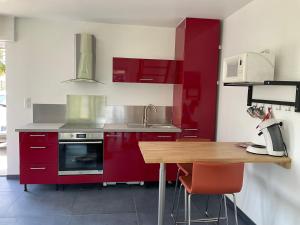 a kitchen with red cabinets and a wooden table at Gite Au sauna de l’Aubach in Scherwiller