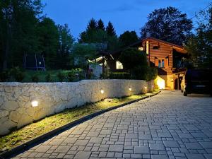 a house with a stone wall next to a driveway at 4TREES Holiday House in Slunj