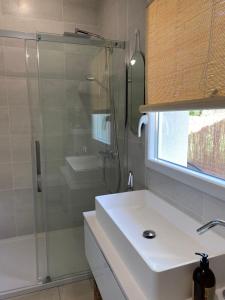 uma casa de banho com um lavatório branco e um chuveiro em La Petite Caserne - Gite 4 étoiles - em Pont-de-Labeaume