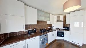 Una cocina con gabinetes blancos y lavadora y secadora. en Orange Apartments Bothwell Road, en Aberdeen