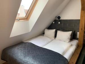 a bed in a attic room with a window at Boutique Gdańsk Apartments in Gdańsk