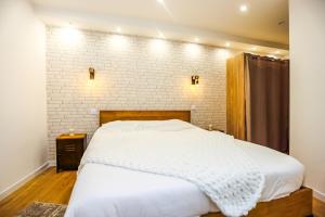 a bedroom with a white bed and a brick wall at Superbe Appartement - Hyper Centre - 2 Chambres - WIFI in Grasse