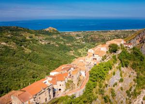 a village on the side of a hill with the ocean at La Pastorella in Maierà