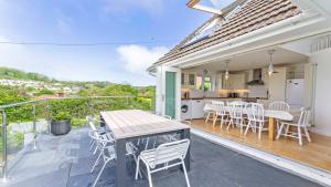a patio with a table and chairs and a kitchen at Rooftops Braunton, Stylish Beach House - Fantastic Views - Hot Tub hire - Sleeps 8 in Braunton
