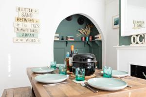 a wooden table with plates and a coffee maker on it at Sprite Cottage, in the heart of Whitstable in Whitstable