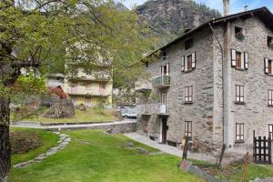 an old stone building in a village with a grass yard at Bellavista in Chiesa in Valmalenco
