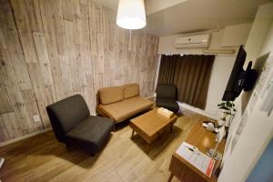 a living room with a couch and a chair and a table at Guest House Re-worth Yabacho1 301 in Nagoya +7 photos