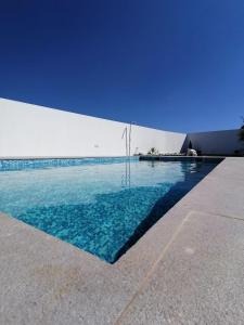 uma piscina com água azul em frente a um edifício em SARDINHA BOÉMIA SUDOESTE By Stay In Alentejo em Fataca