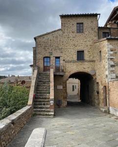 a stone building with a staircase leading to a doorway at Brunhouse in San Quirico dʼOrcia