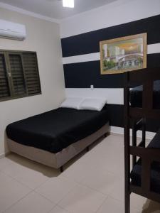Bett in einem Zimmer mit einer schwarz-weißen Wand in der Unterkunft Recanto Cote Gil in Olímpia