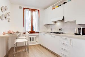 cocina con armarios blancos, mesa y sillas en Piazza San Marco Cozy Apartment x4, en Venecia