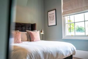 een slaapkamer met een bed met roze kussens en een raam bij The Grand at Dukes Townhouse in York