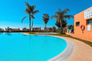 una gran piscina junto a un edificio con palmeras en R25 Modern bright 2 bedroom apartment, en Marbella