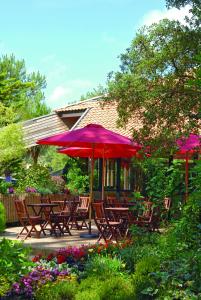 a patio table with umbrellas in front of a house at Résidence Vacances Bleues Domaine de l'Agréou in Seignosse