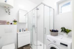 a white bathroom with a shower and a washing machine at Miro in Senj +23 photos