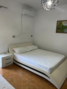 1 dormitorio con cama blanca y mesita de noche en Rooms for rent habipi, en Vlorë