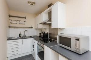 a kitchen with white cabinets and a microwave at Vivid Apartment in Central London in London