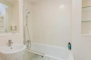 a white bathroom with a shower and a sink at Vivid Apartment in Central London in London