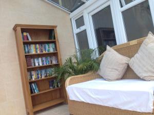 a couch in a room with a book shelf with books at ** SPECIAL OFFER ** Half price - Book your Double room with us now in Willand