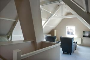an attic room with two chairs and a tv at Hotel-Restaurant Thuis! in Dinteloord