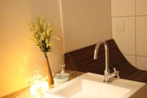 uma casa de banho com um lavatório e um vaso de flores num balcão em Arraialferias Suites em Arraial do Cabo